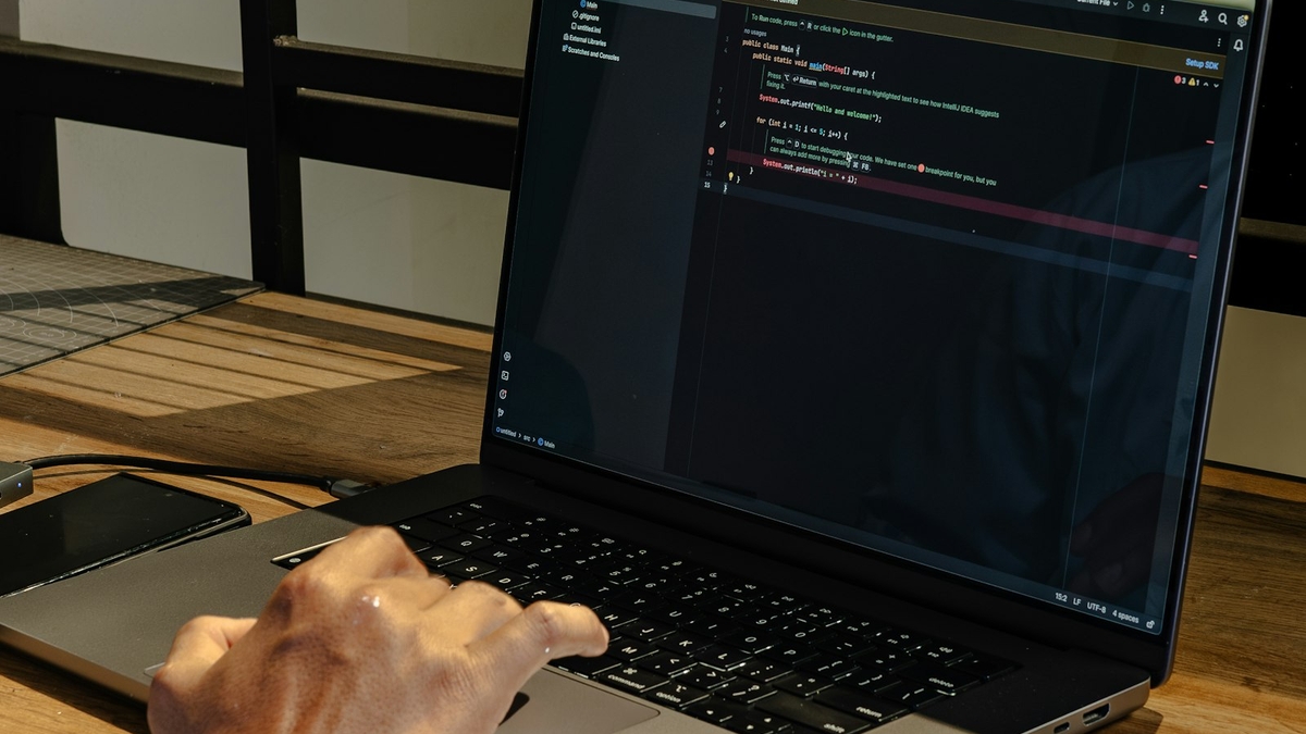 programmer typing on a laptop with code on screen