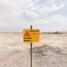 乾いた草地に立つ多言語の DANGER MINES 警告標識